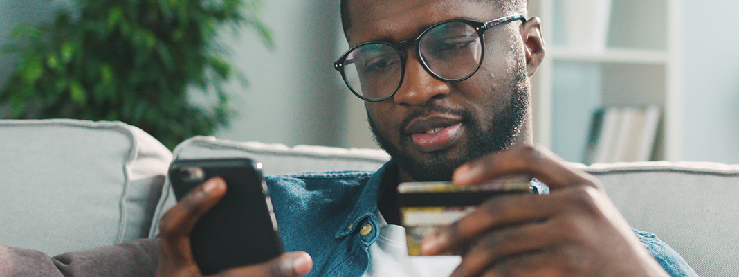 Young man making a purchase on his phone with his credit card