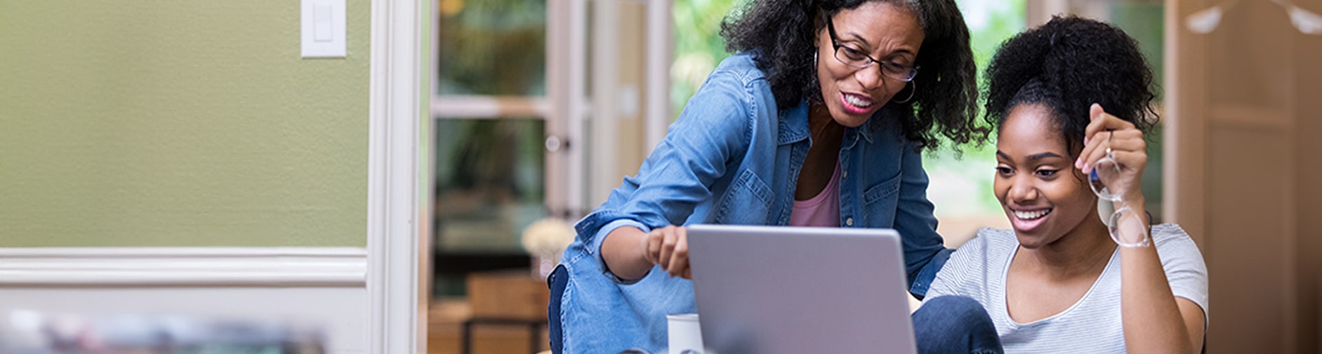 Teen daughter and mother looking at a laptop screen together