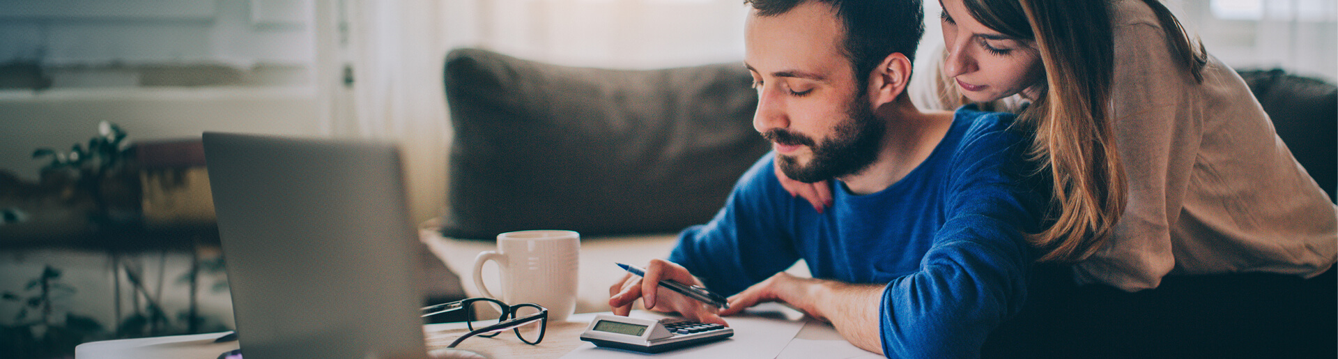 Young couple using a calculator in their home