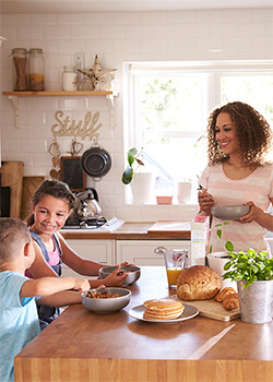 Two kids in the kitchen with their mom