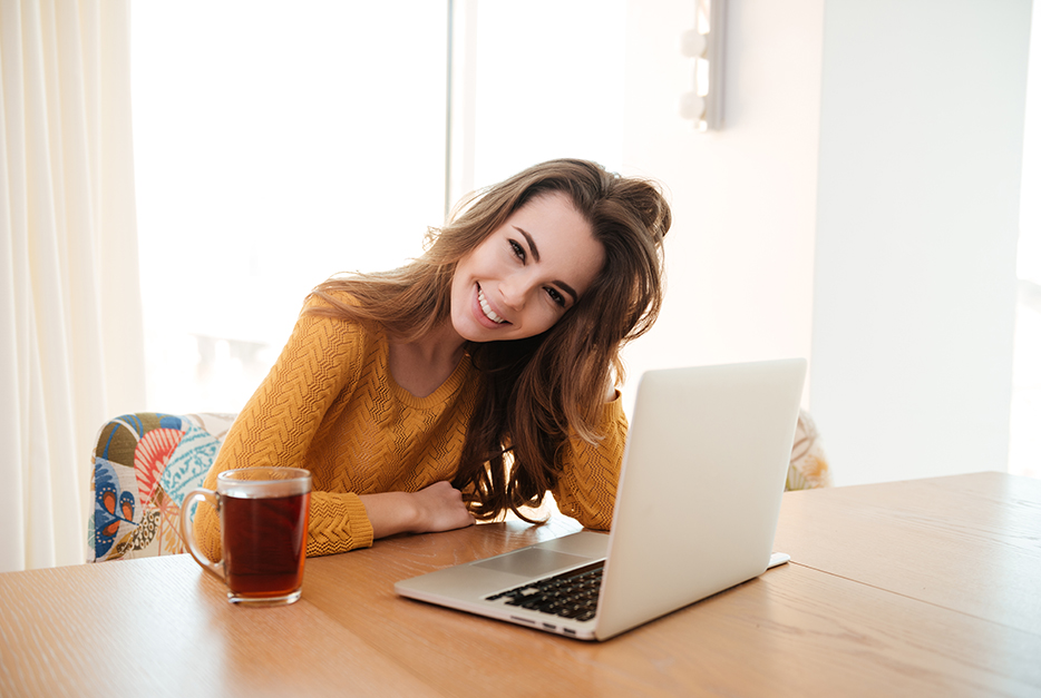 Young woman sitting with a laptop and smiling