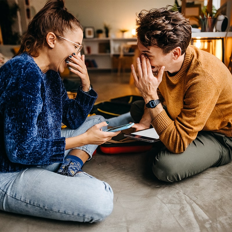 young couple laughing on the floor of their apartment