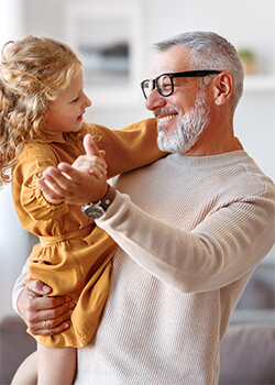 A man holding a little girl and they are smiling at each other.