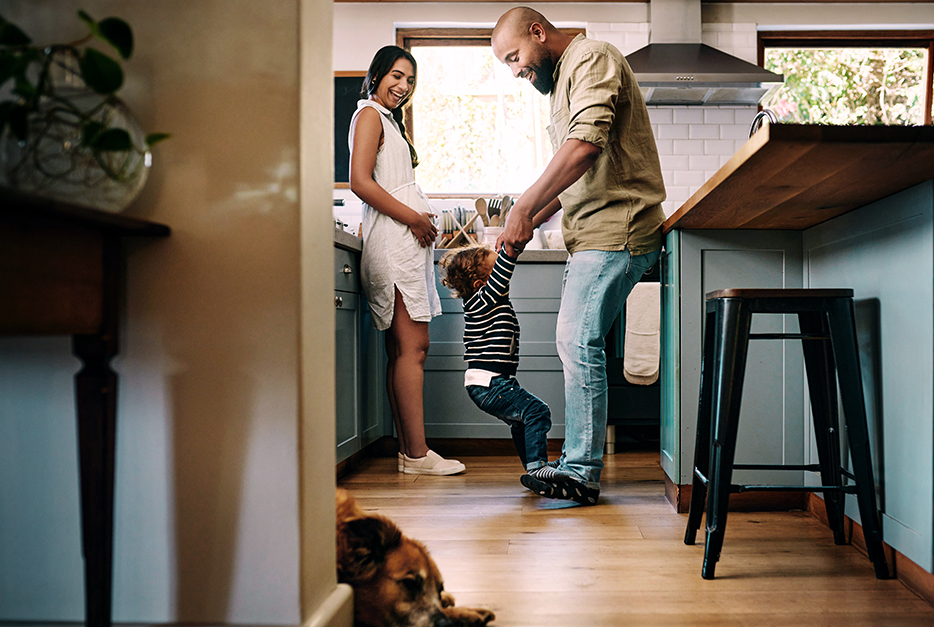 Couple standing in the kitchen together with their young daughter