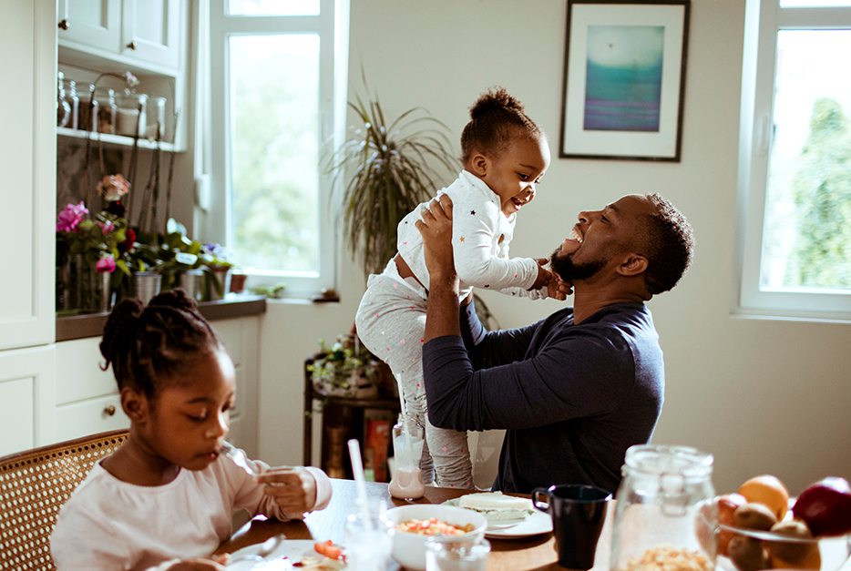 Man holding his daughter at a kitchen table
