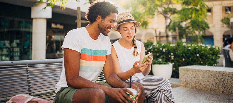 Two people sitting on a concrete bench, looking at phone together