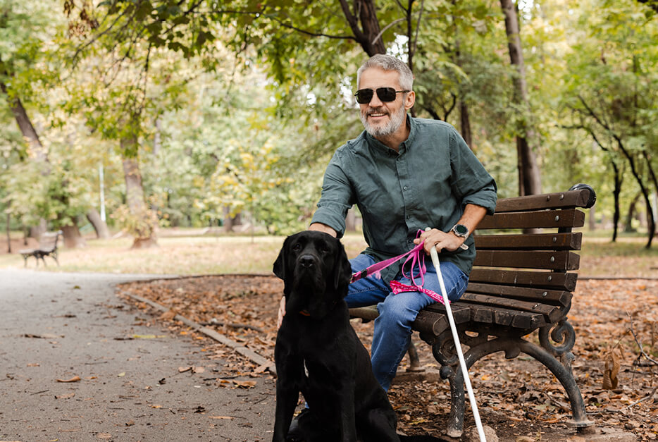 Blind man sitting on a bench with his dog 