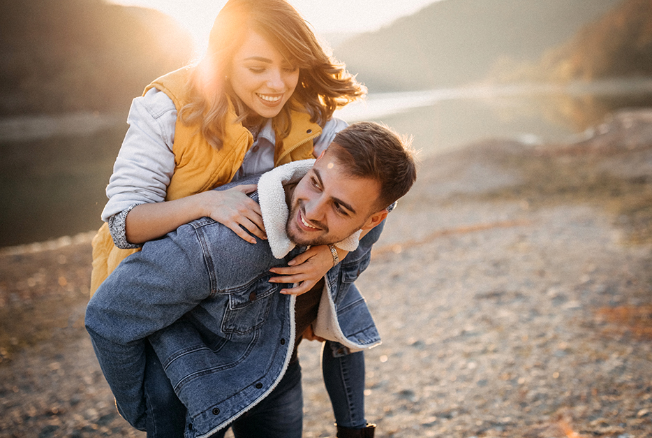 Young couple standing on a shore giving a piggyback ride