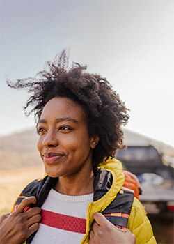 Woman smiling with backpack, about to set out on a hiking adventure.