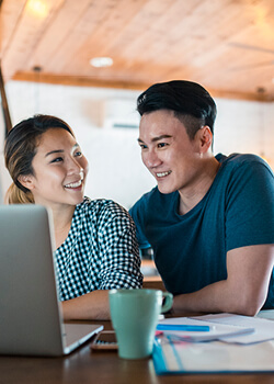 two people drinking coffee and looking at a laptop