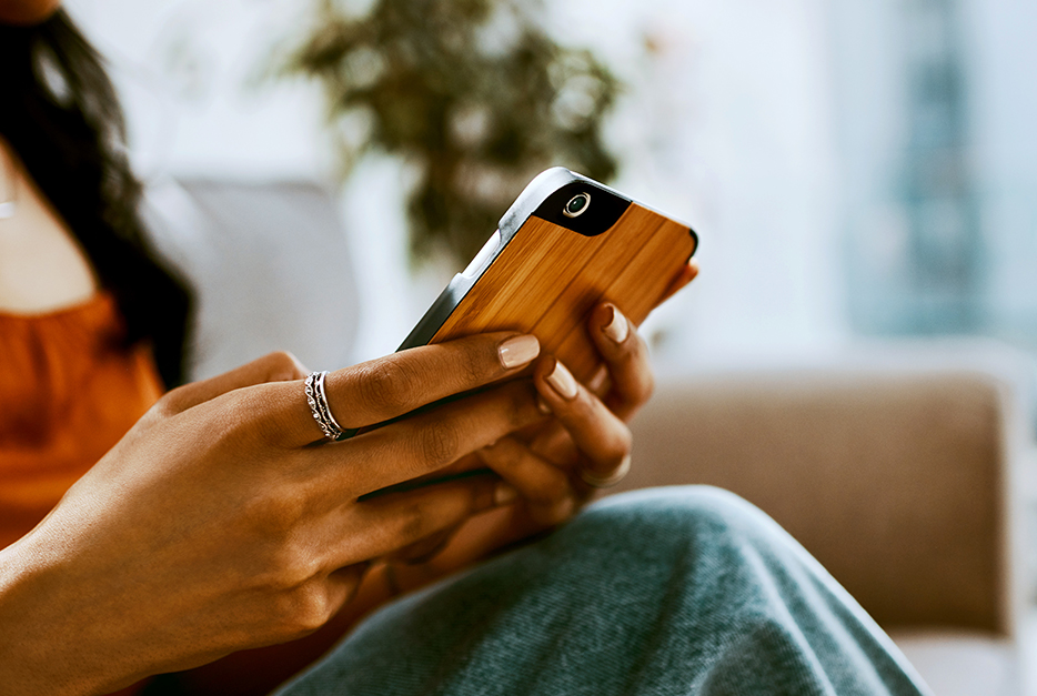 Woman holding her smartphone while sitting on a couch