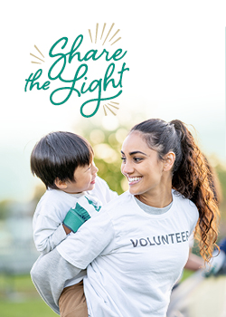 woman with volunteer on t-shirt giving a kid a piggy back ride