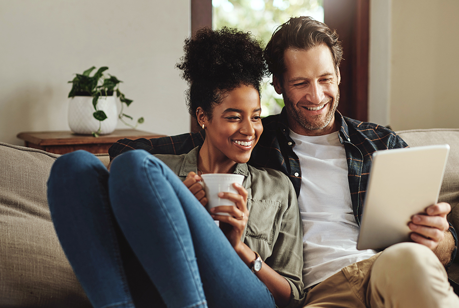 Couple sitting on a couch looking at a tablet