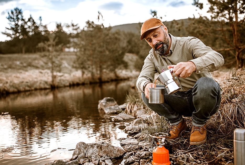 Man sitting by the shore making coffee