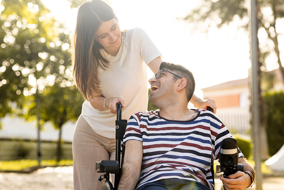 Woman pushing man in wheelchair