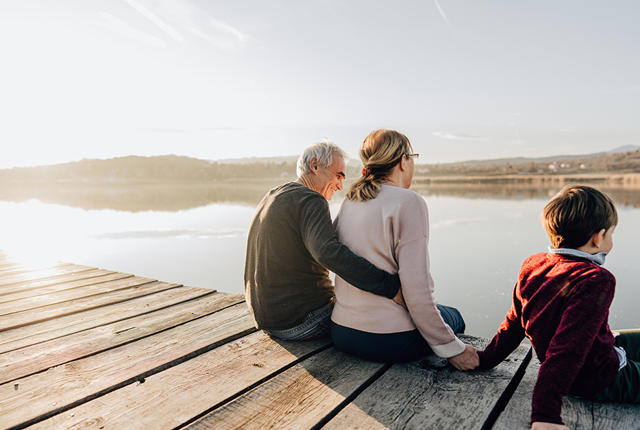 Couple sitting on a dock with their grandson