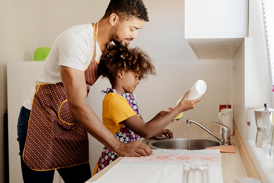 Man cleaning dishes with his daughter