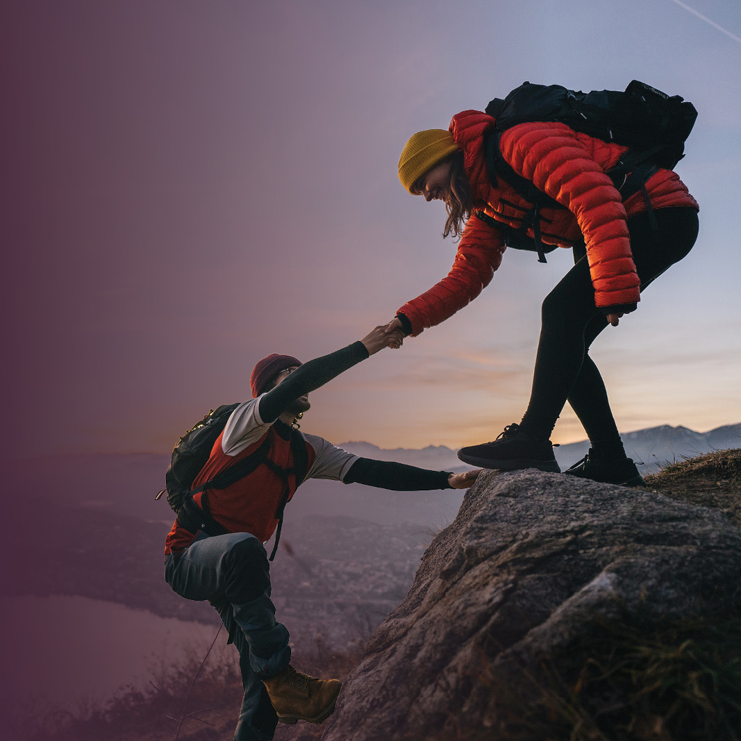hikers helping each other up a hill