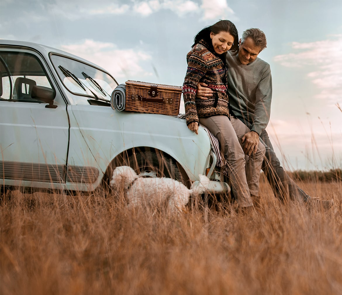 Man and women in field on car