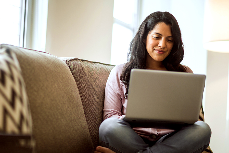 Woman sitting on her couch with her laptop