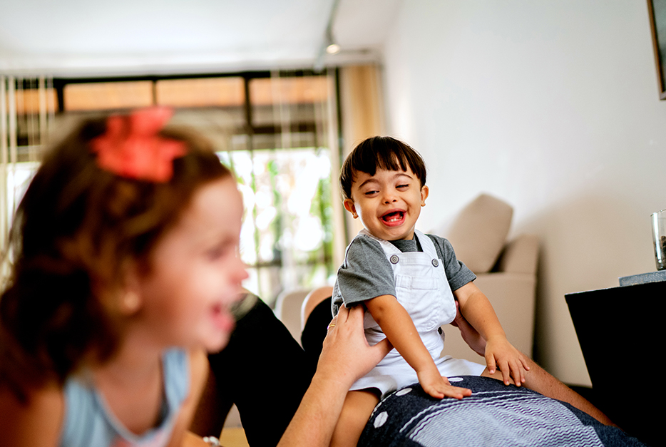 Young boy laughs while sitting on his dad