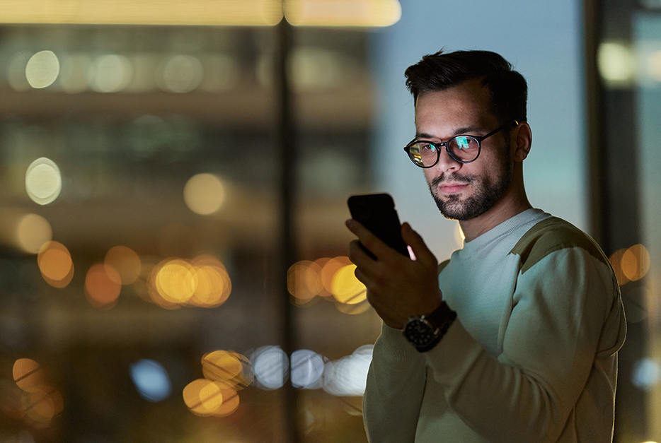 Man standing in front of his window with his smartphone