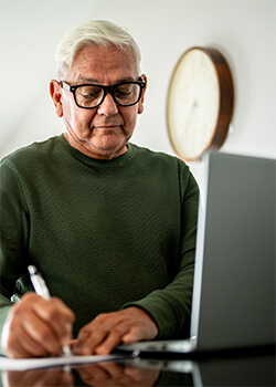 Man wearing glasses, sitting at a table, and making notes