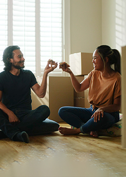young couple eating pizza with moving boxes