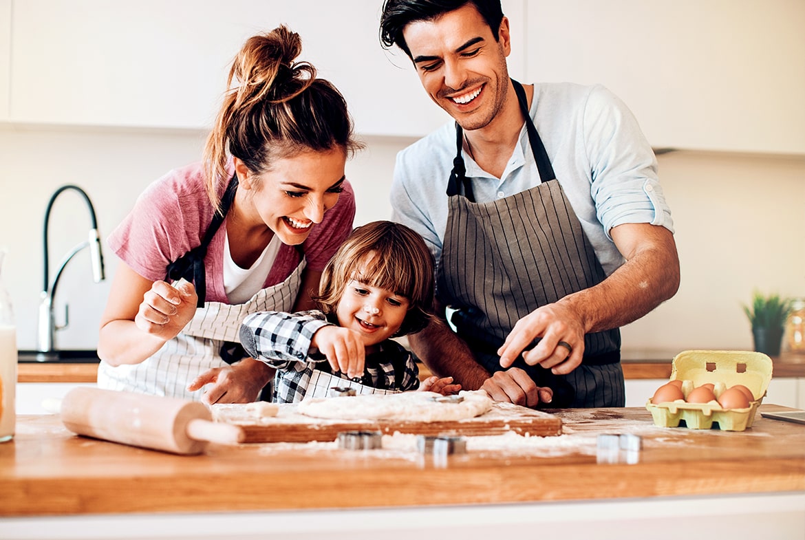 young mom and dad making cookies with child