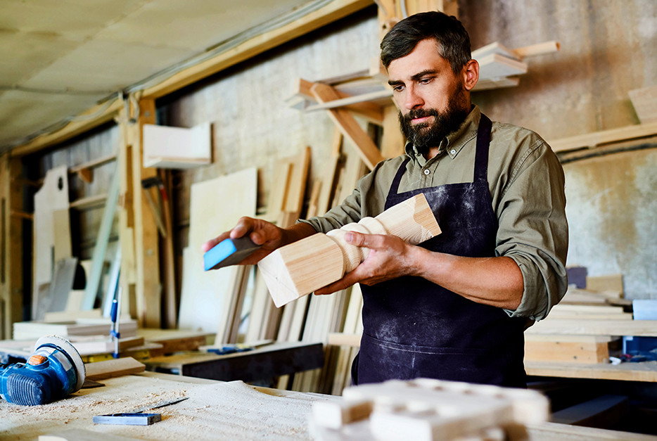 Carpenter sanding a table leg