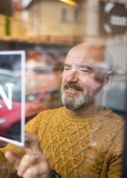 Man flipping a sign to open in the glass door