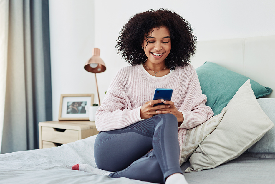 Woman sitting on her bed with her smartphone