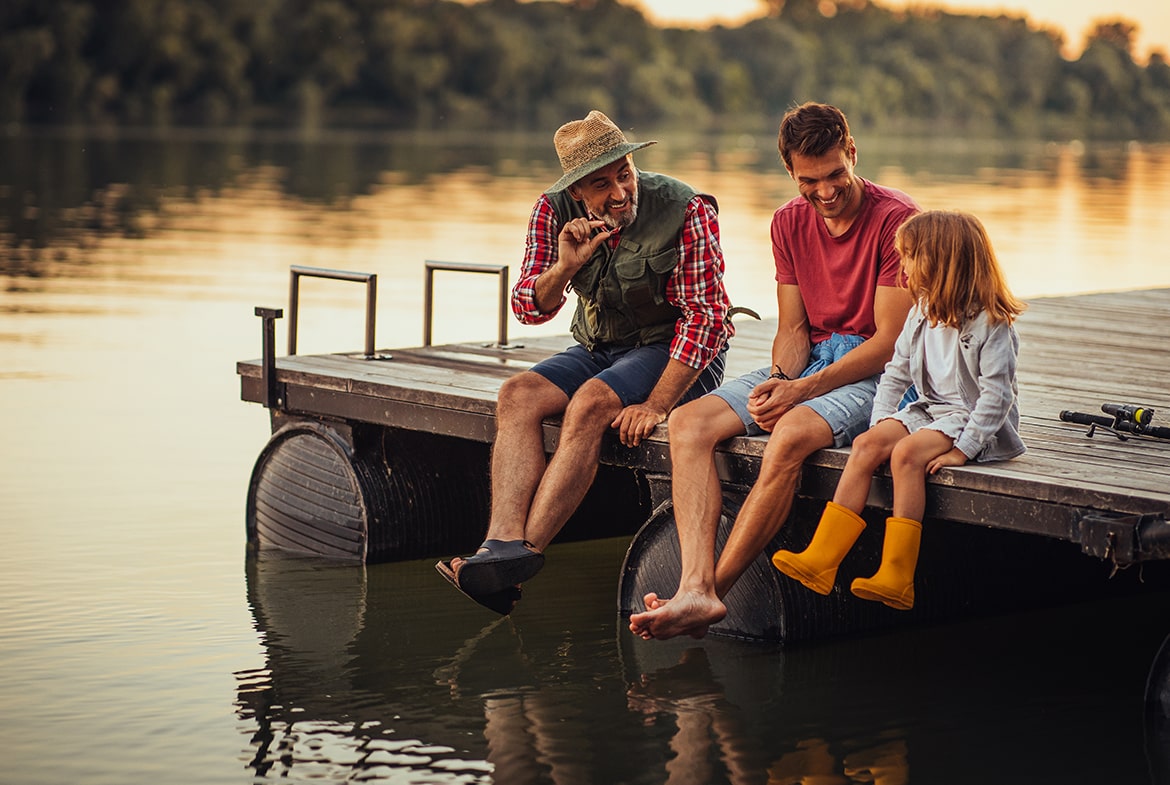 grandpa and dad laughing with little girl on a dock