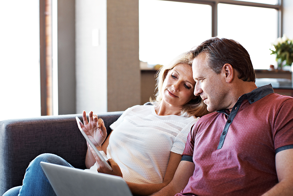 Couple sitting on a couch looking at a laptop