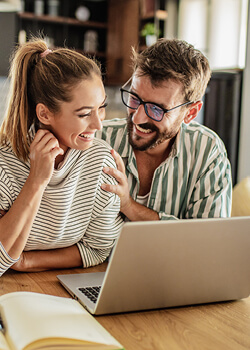 two people drinking coffee and looking at a laptop